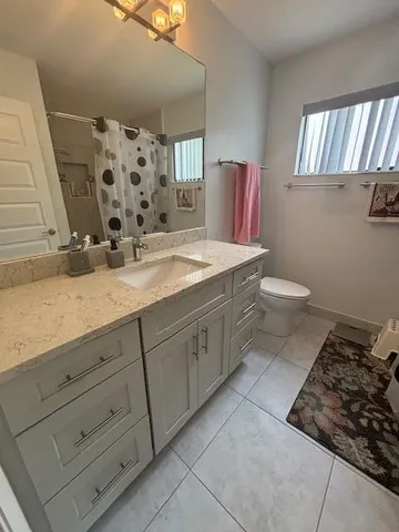 a spacious bathroom with a granite countertop toilet sink and mirror
