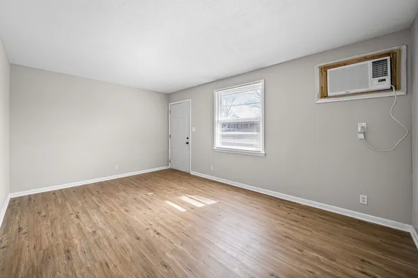 a view of an empty room with wooden floor and a window