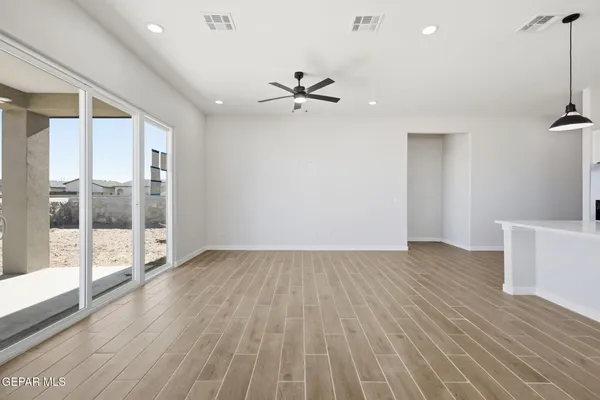 a view of an empty room with a window and wooden floor