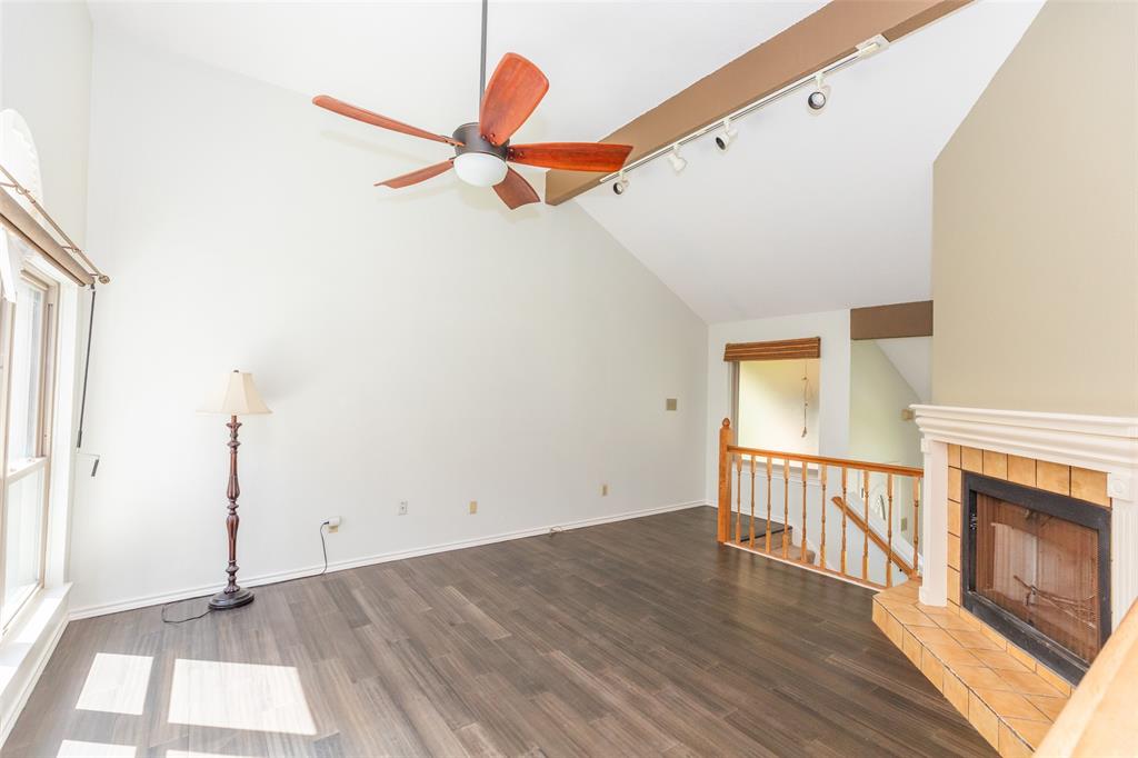 6545 Los Rios Drive Mesquite, TX 75150 - Photo 4 of 9 Living area featuring vaulted ceilings, wood-finish flooring, a fireplace with a tiled hearth, a wooden railing, and a ceiling fan