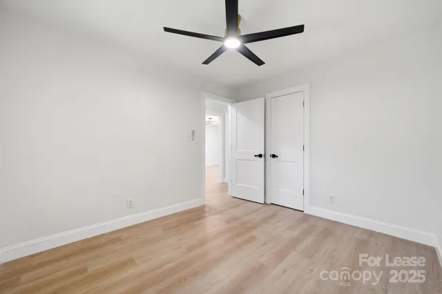 an empty room with a ceiling fan and wooden floor