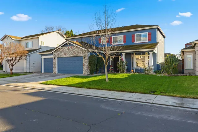 a view of a brick house with a large windows and a yard with plants and large trees