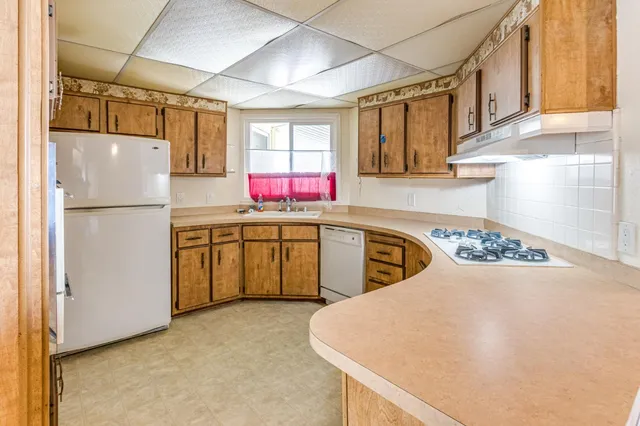 a white refrigerator freezer and a stove sitting inside of a kitchen