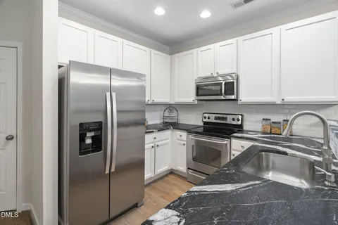 a kitchen with stainless steel appliances granite countertop a sink a stove and a refrigerator