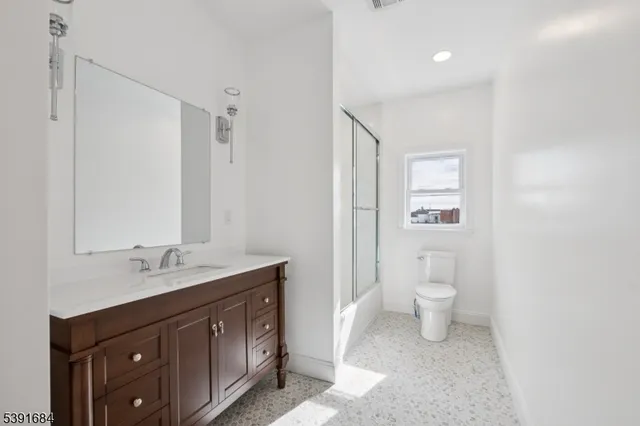 a spacious bathroom with a granite countertop sink toilet and a mirror