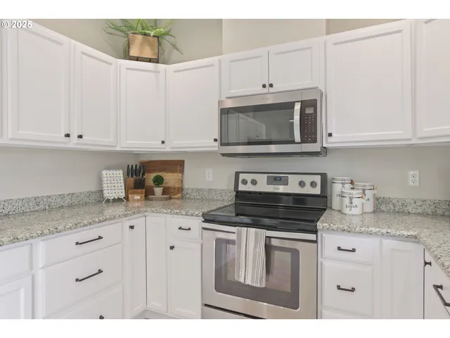 a kitchen with granite countertop white cabinets and stainless steel appliances