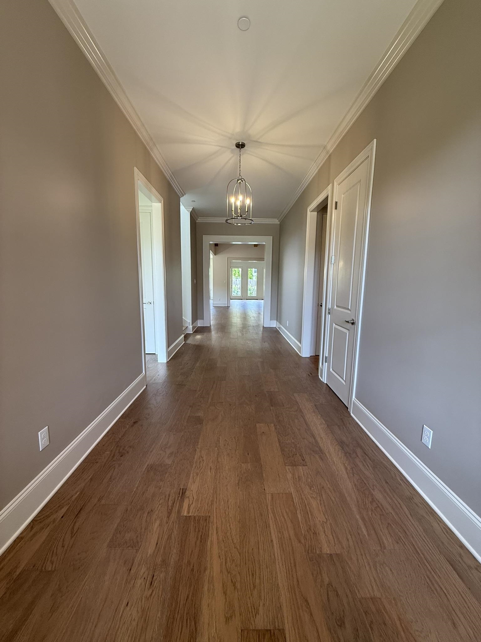 10132 Rokeby Farm Lane Collierville, TN 38017 - Photo 2 of 24 Long hallway featuring wood-finish flooring, white crown molding, and a drum pendant light fixture