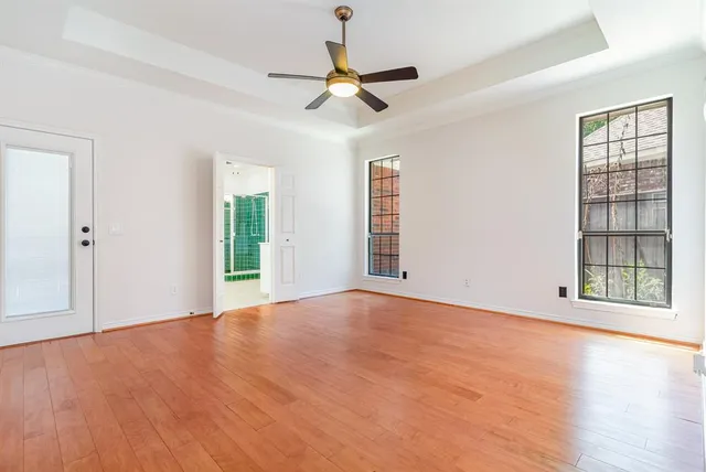 a view of an empty room with a window and wooden floor