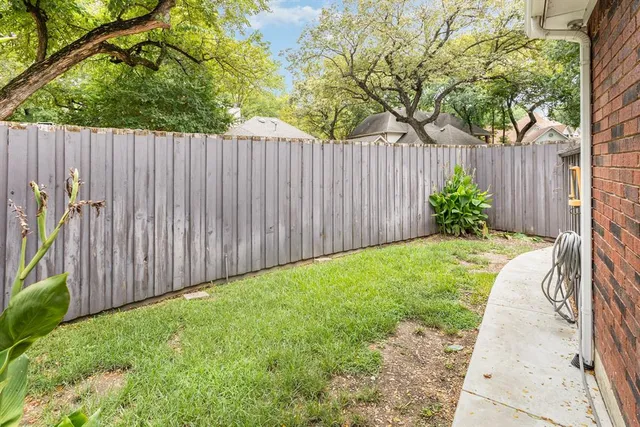 a view of a backyard with a trees and wooden fence