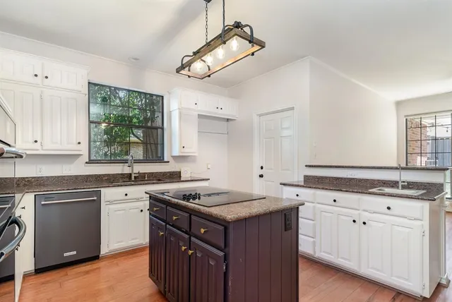 a kitchen with granite countertop a sink stove cabinets and window