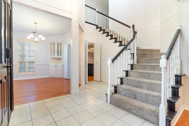 a view of staircase with white walls and chandelier