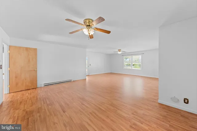 an empty room with wooden floor chandelier fan and windows