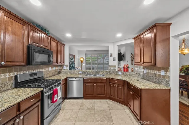 a kitchen with granite countertop a stove top oven microwave and refrigerator
