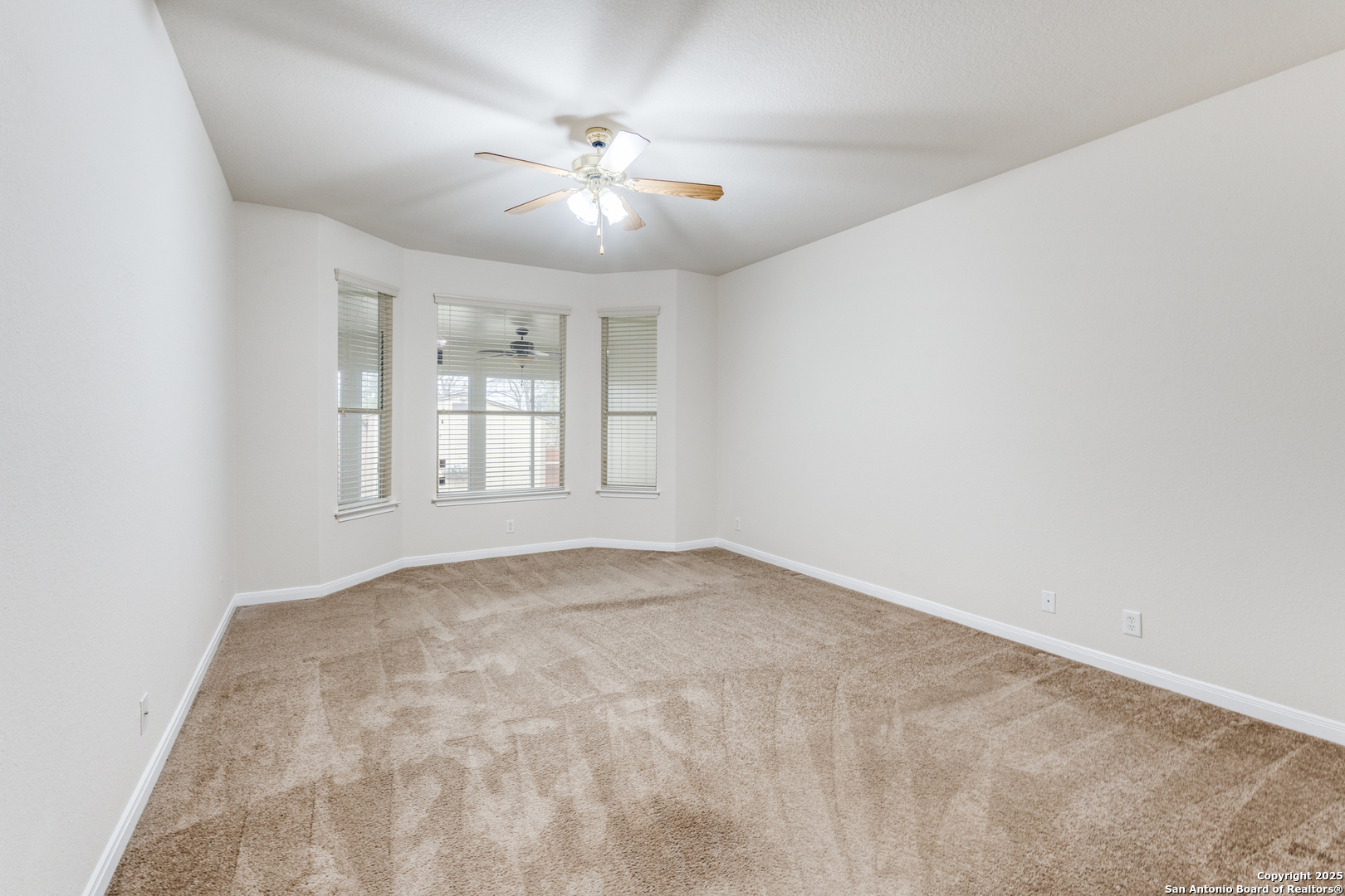 1935 Walter Raleigh Windcrest, TX 78239 - Photo 11 of 27 an empty room with windows and chandelier fan