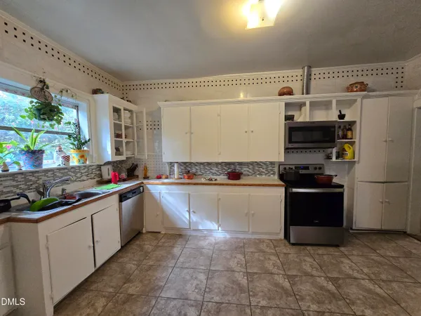 a kitchen with stainless steel appliances a sink a window and cabinets