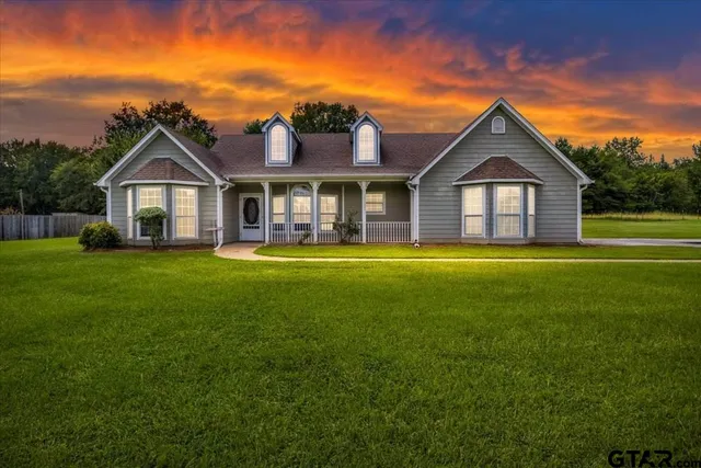 a view of a house with a big yard and large trees