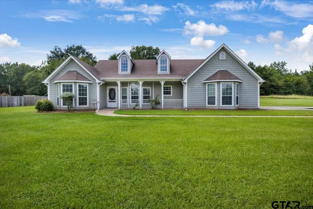 a front view of a house with a garden and trees