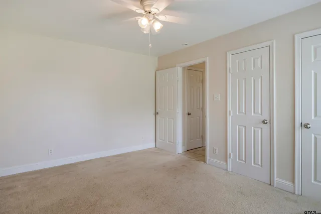 a view of an empty room and chandelier fan