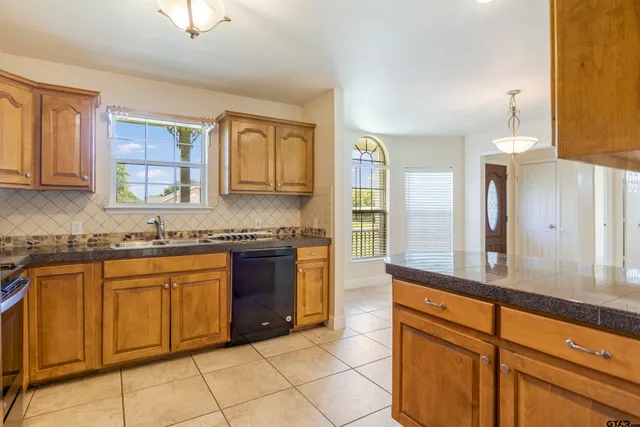 a large kitchen with granite countertop a sink and cabinets
