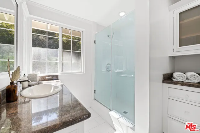 a spacious bathroom with a granite countertop sink a mirror and shower