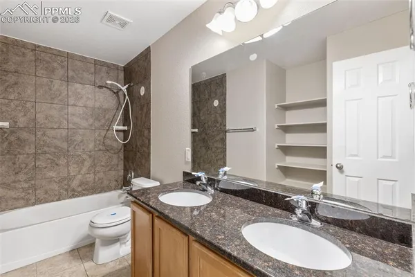 a bathroom with a granite countertop sink toilet a mirror a vanity and shower