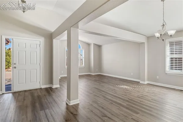 an empty room with wooden floor windows and cabinet