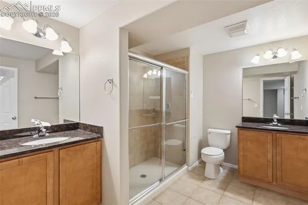 a bathroom with a granite countertop sink a toilet a mirror and shower