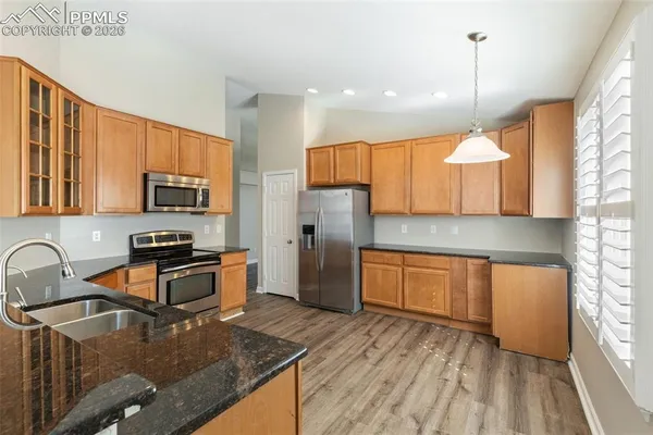 a kitchen with stainless steel appliances granite countertop a sink stove refrigerator and microwave