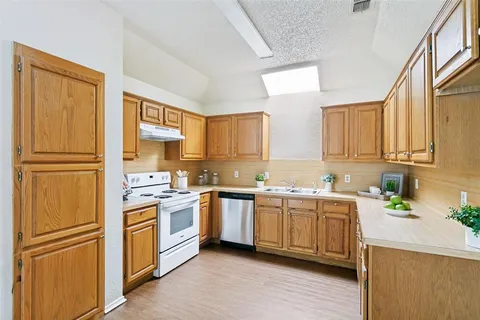a kitchen with stainless steel appliances granite countertop a refrigerator a sink dishwasher a stove with wooden cabinets and floor