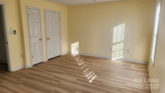 a view of a bedroom with wooden floor and windows