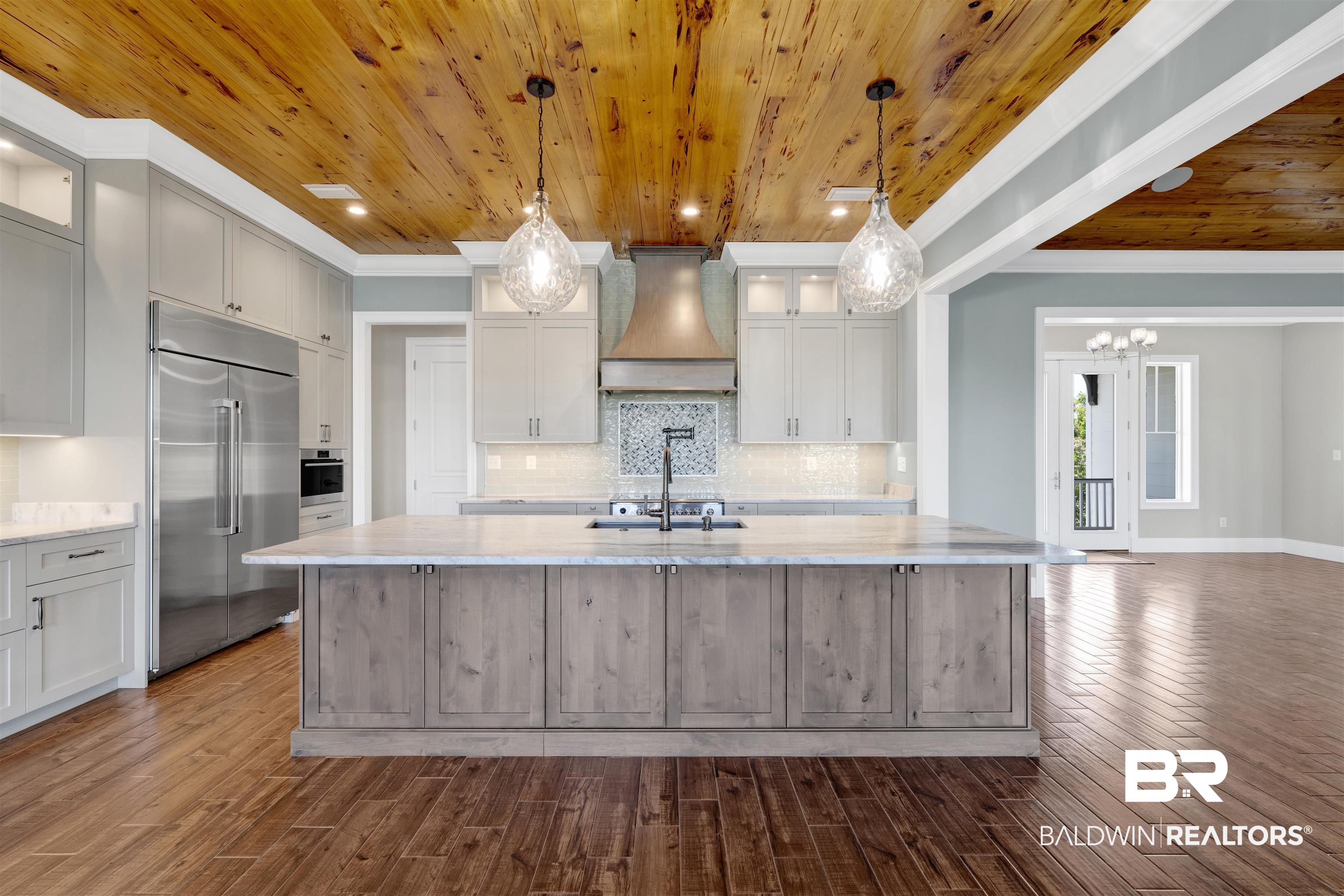 31729 River Road Orange Beach, AL 36561 - Photo 14 of 54 Two tone kitchen featuring glass insert cabinets, light stone counters, stainless steel appliances, a large island, and backsplash
