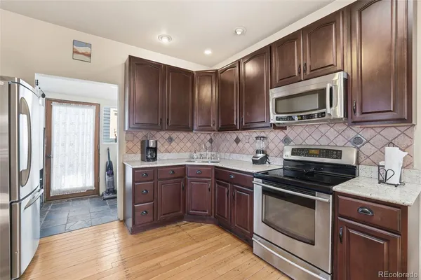 a kitchen with granite countertop wooden cabinets a stove top oven and stainless steel appliances
