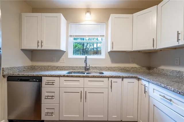 a kitchen with granite countertop white cabinets and a sink