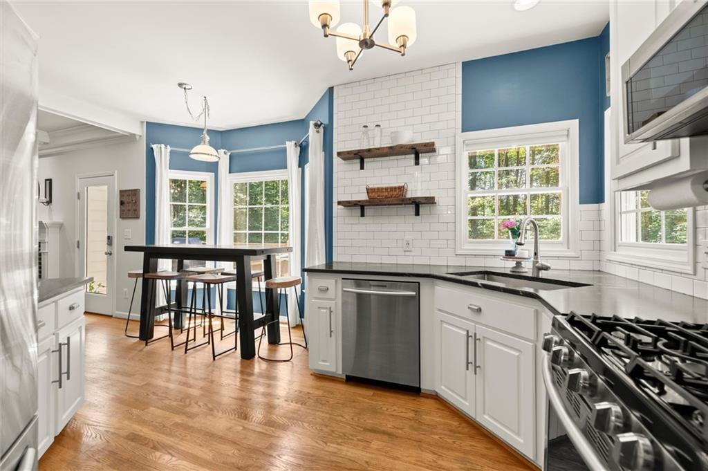 313 Thorntree Lane Canton, GA 30115 - Photo 16 of 51 a kitchen with stainless steel appliances granite countertop a stove a sink dishwasher a dining table and chairs with wooden floor
