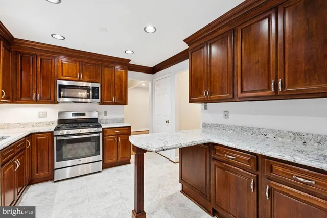 a kitchen with granite countertop wood cabinets stainless steel appliances and a sink
