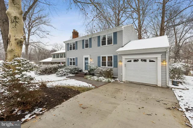 a view of a white house with a large trees next to a road