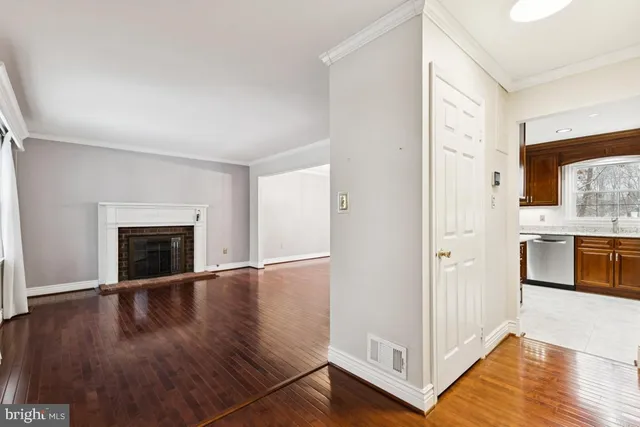 a view of a hallway with wooden floor and a kitchen