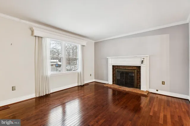 an empty room with wooden floor fireplace and windows