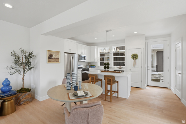 7338 South Seven Tree Lane, Unit 75 Midvale, UT 84047 - Photo 11 of 30 Kitchen featuring white cabinets, a kitchen breakfast bar, stainless steel appliances, a center island, and light wood-type flooring
