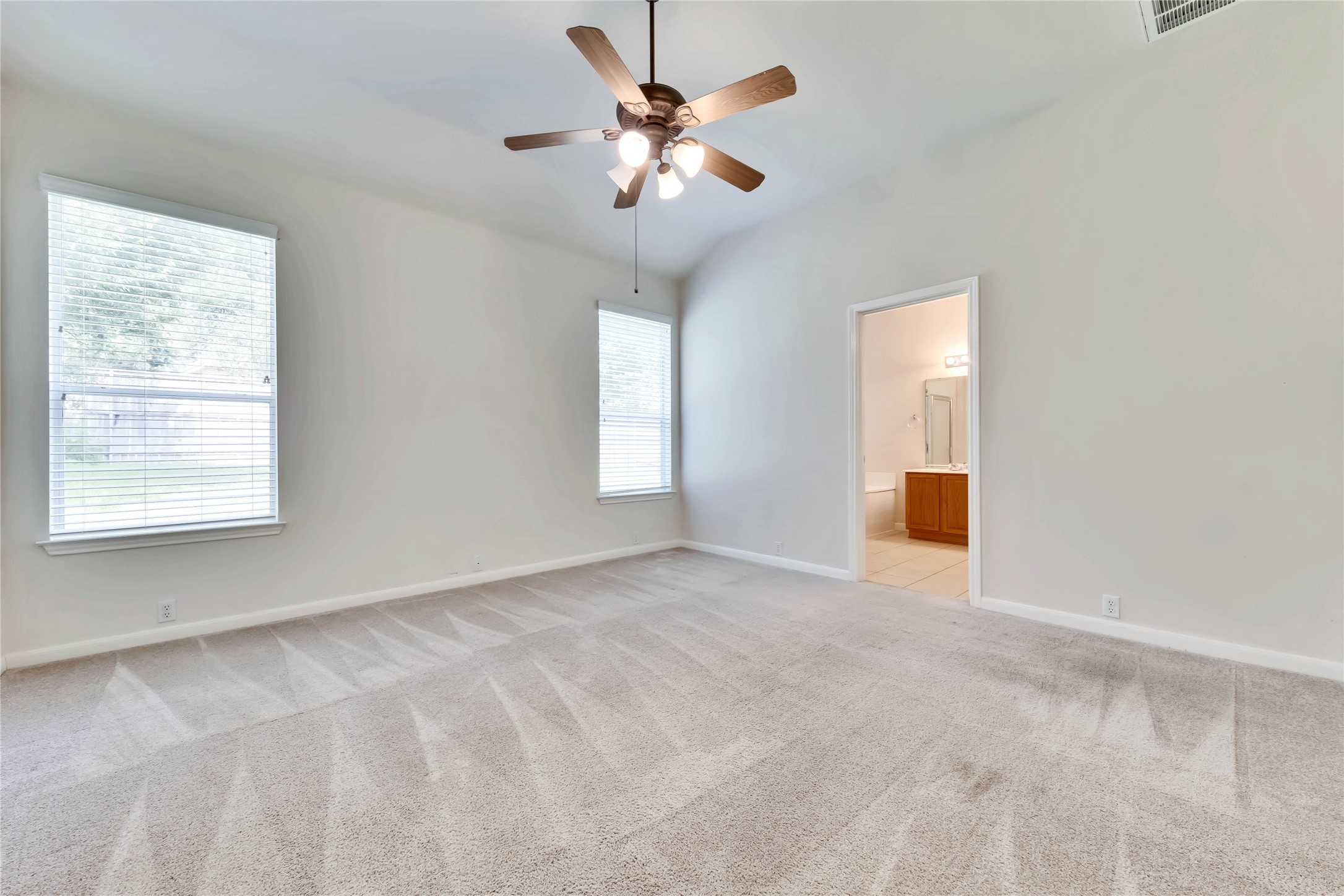 2133 Paradise Ridge Drive Round Rock, TX 78665 - Photo 16 of 22 Carpeted room with a vaulted ceiling, ceiling fan with integrated lighting, and two windows with blinds