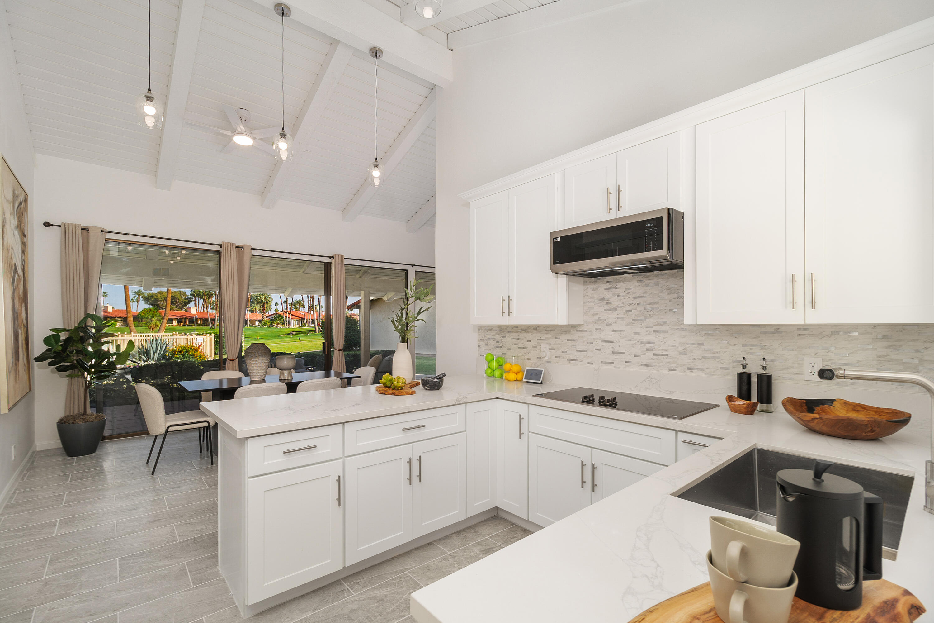 49835 Adelito Circle La Quinta, CA 92253 - Photo 6 of 36 a kitchen filled with a white stove top oven a sink a dining table and chairs