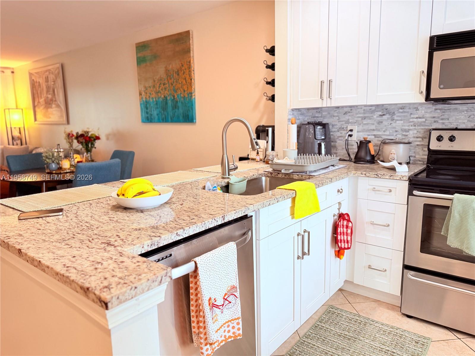 3370 Beau Rivage Drive, Unit 4Q Pompano Beach, FL 33064 - Photo 19 of 31 a kitchen with a sink a stove and white cabinets