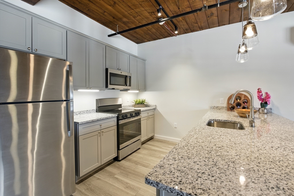 55 Sterling Street, Unit 314 Clinton, MA 01510 - Photo 10 of 36 a kitchen with granite countertop a refrigerator stove and microwave