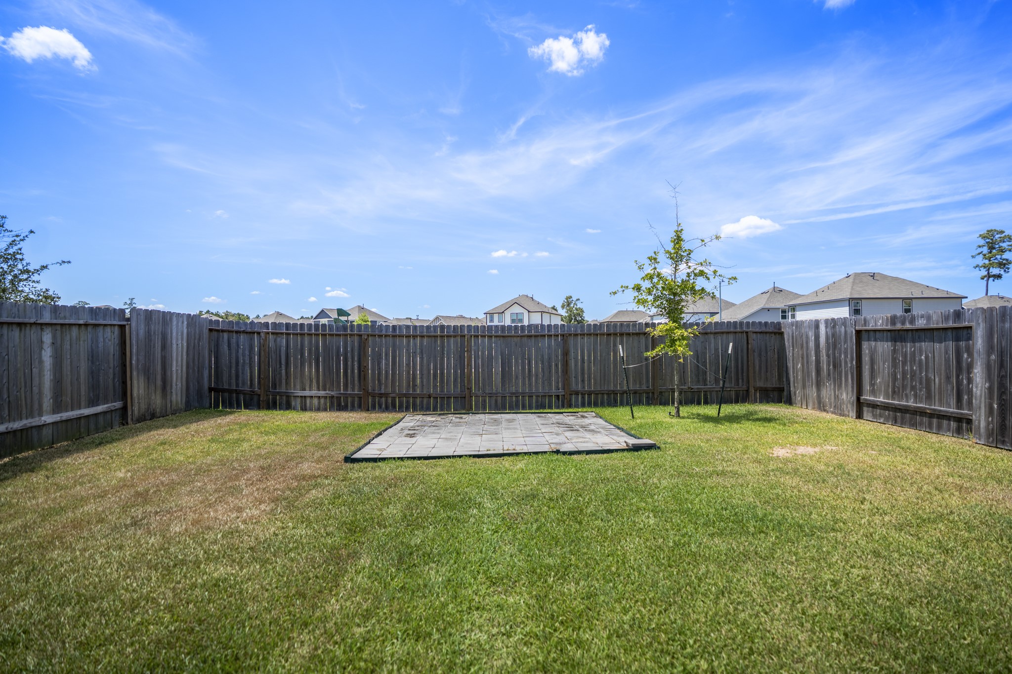 2355 Mount Locke Path Conroe, TX 77301 - Photo 41 of 47 Taking one more look across the backyard, the open lawn stretches toward the rear fence with no neighbors directly behind, giving the space a little more breathing room. The automatic sprinkler system helps simplify upkeep, leaving more time to enjoy the yard instead of fussing over it.