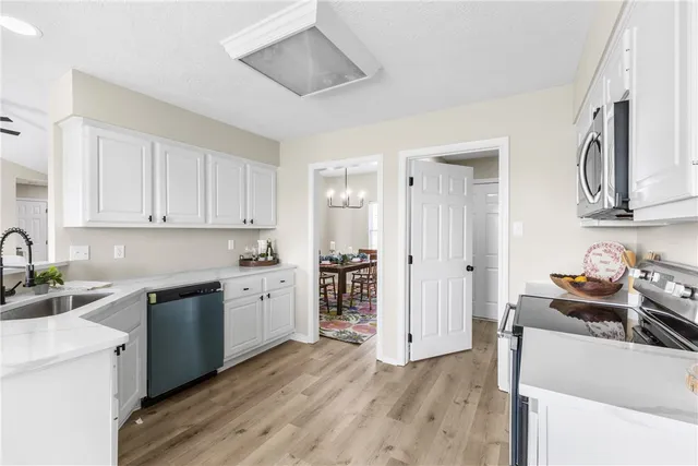 a kitchen with a sink cabinets stainless steel appliances and wooden floor