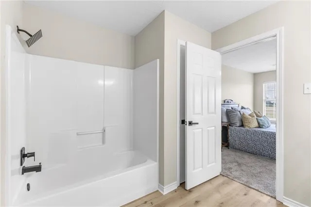 a bathroom with a tub shower and bedroom