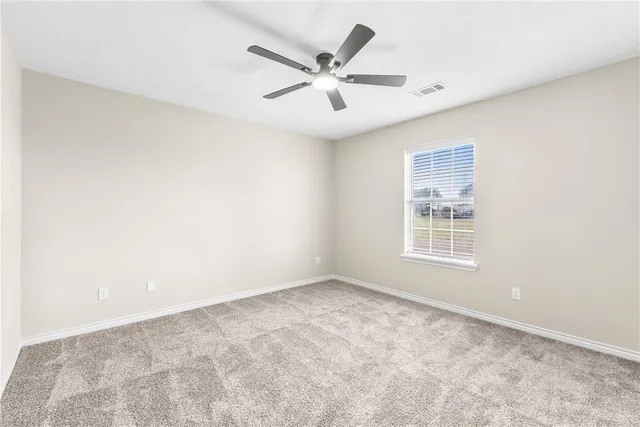 an empty room with window and ceiling fan