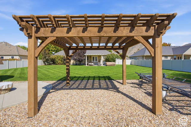 1447 Meadow Lane Mapleton, UT 84664 - Photo 44 of 67 Wood pergola over a gravel patio, featuring a manicured lawn and a white privacy fence