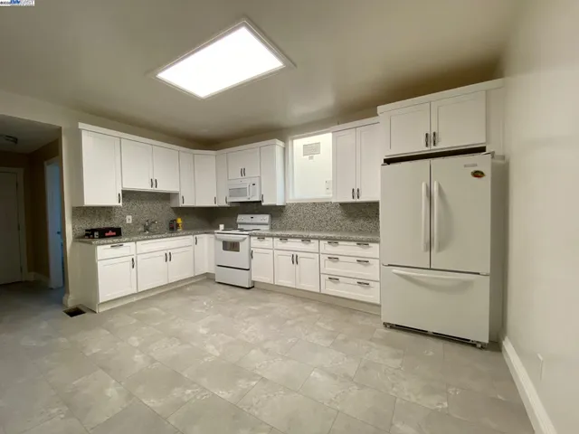 a kitchen with white cabinets and white appliances