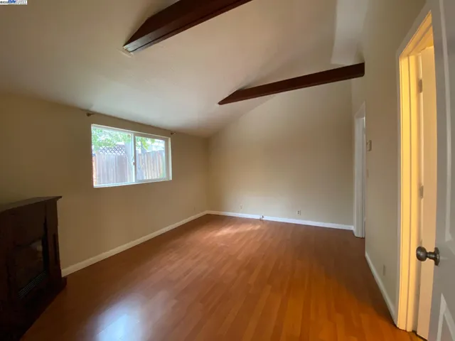 a living room with stainless steel appliances wooden floor and a large window